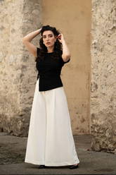 a lady in an irregular black top and a pair of white wide leg pants